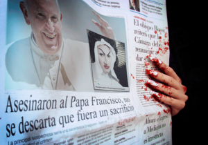 Portada de Un enorme corazón. Ocupando casi toda la imagen la portada de un diario anunciando el asesinato del Papa Francisco, con una foto de Psicógena Lapsus como la presunta criminal. Sosteniendo la página, unas manos con largas uñas blancas ensangrentadas, ensuciándolo todo.